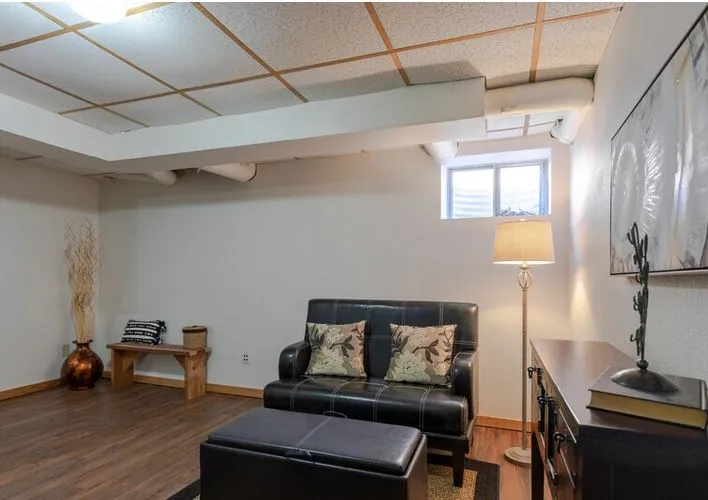 Finished basement with a loveseat, floor lamp and laminate floor